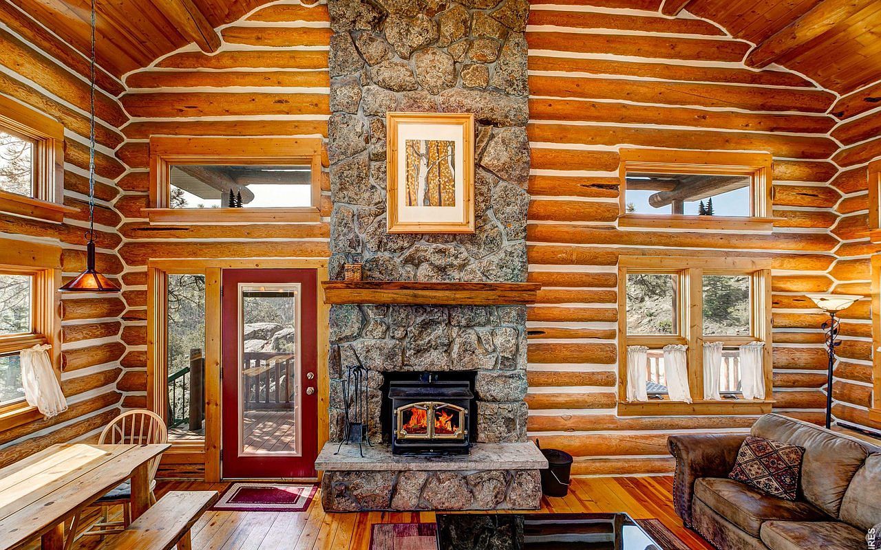 The great room fireplace — stone hearth with wood-burning stove, red door onto the deck